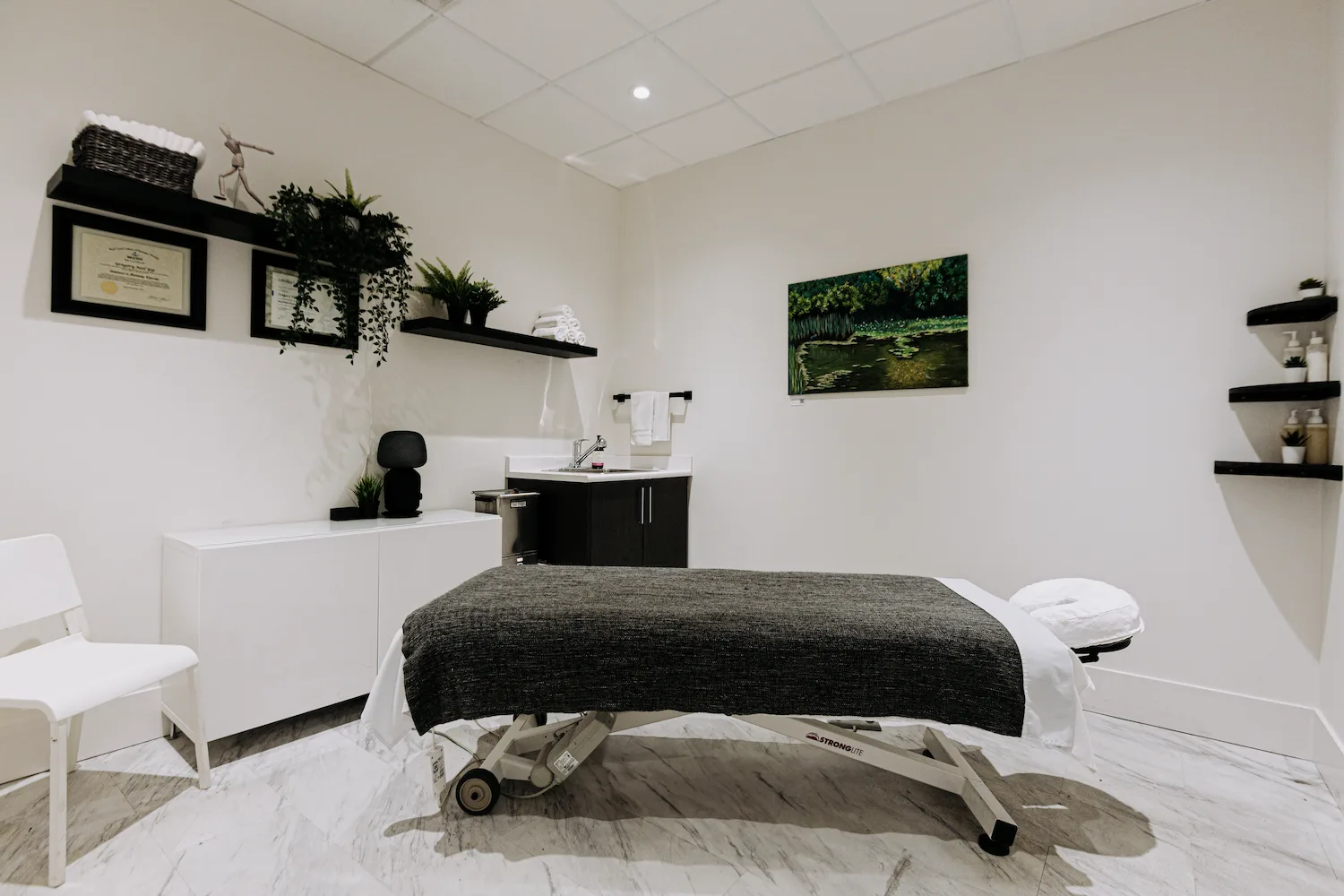 Treatment room at Launch Rehab North Burnaby with marble flooring and registered therapist credentials on the wall