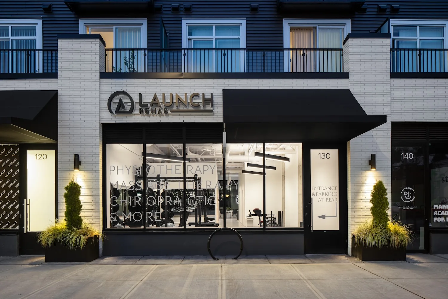 Launch Rehab Richmond studio exterior on Williams Rd, with the illuminated logo above a black awning and the gym floor visible through the storefront windows